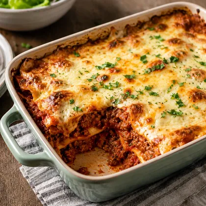 Large baked beef and lentil lasagne with golden cheese topping and a portion removed