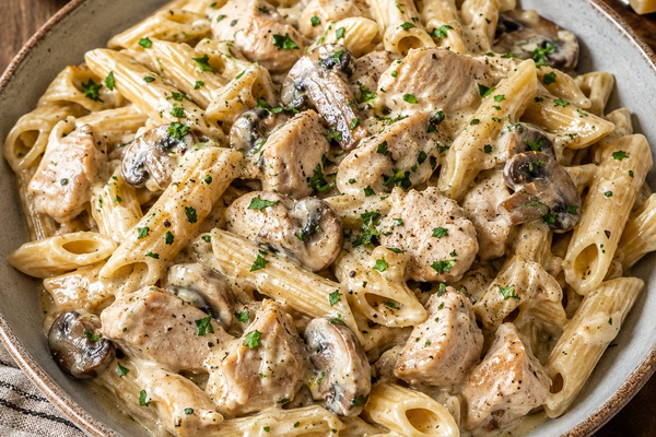 Creamy penne pasta with pieces of chicken and sliced mushrooms, finished with parsley and black pepper