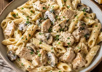 Creamy penne pasta with pieces of chicken and sliced mushrooms, finished with parsley and black pepper