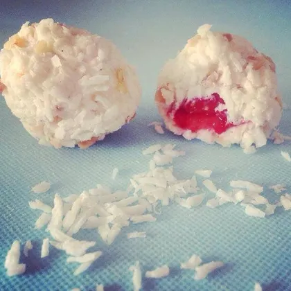 Two coconut-coated chocolate yoghurt balls, one cut open to show a strawberry centre